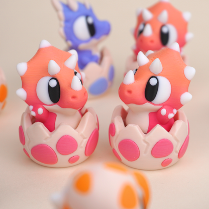Baby Dinosaur Clicker Toy, Triceratops character in its eggshell, close-up pair view
