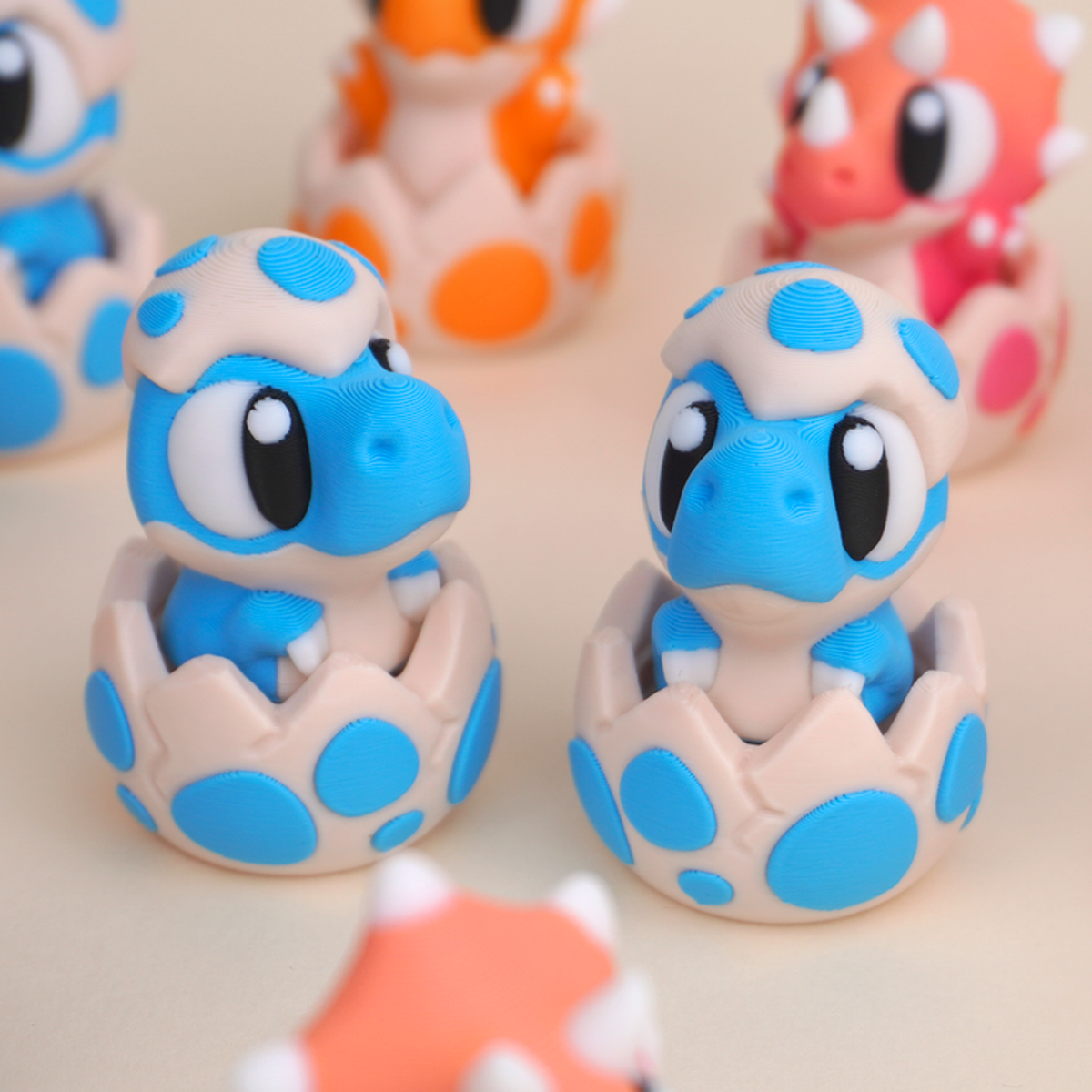 Baby Dinosaur Clicker Toy, blue dinosaur character in its eggshell, close-up pair view
